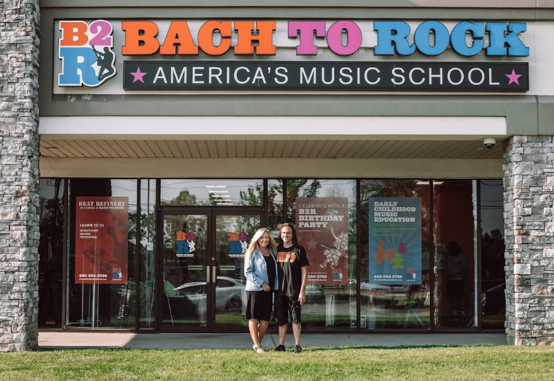 two bach to rock music school franchise owners in front of their store